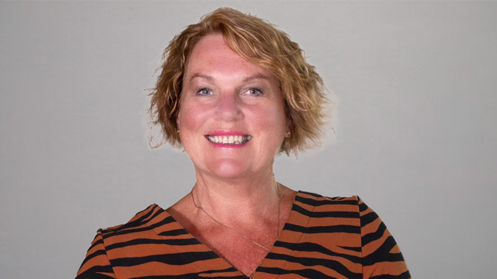 A headshot of Jan Buchanan, wearing an organge and black striped top. 