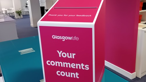A pink and white letterbox style box with text Glasgow Life Your comments count printed on it
