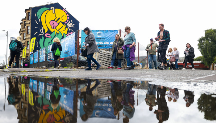 A group of people follow the Govan Mural Trail