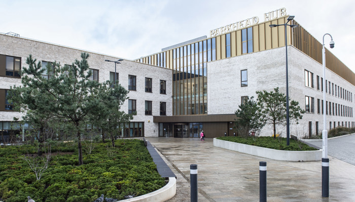 Greenery lines the path to the front of a health, social care and community facility